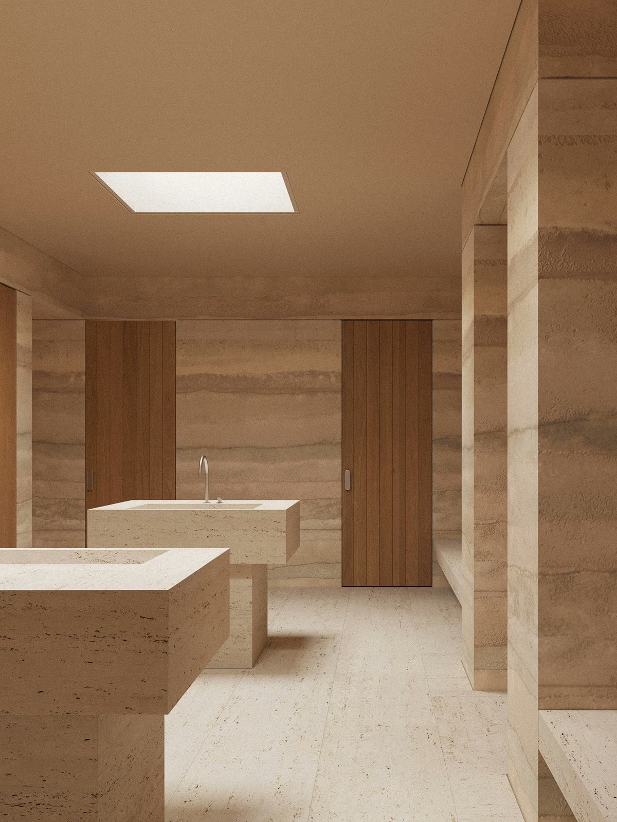 A travertine bath with a carved stone sink and warm wood doors