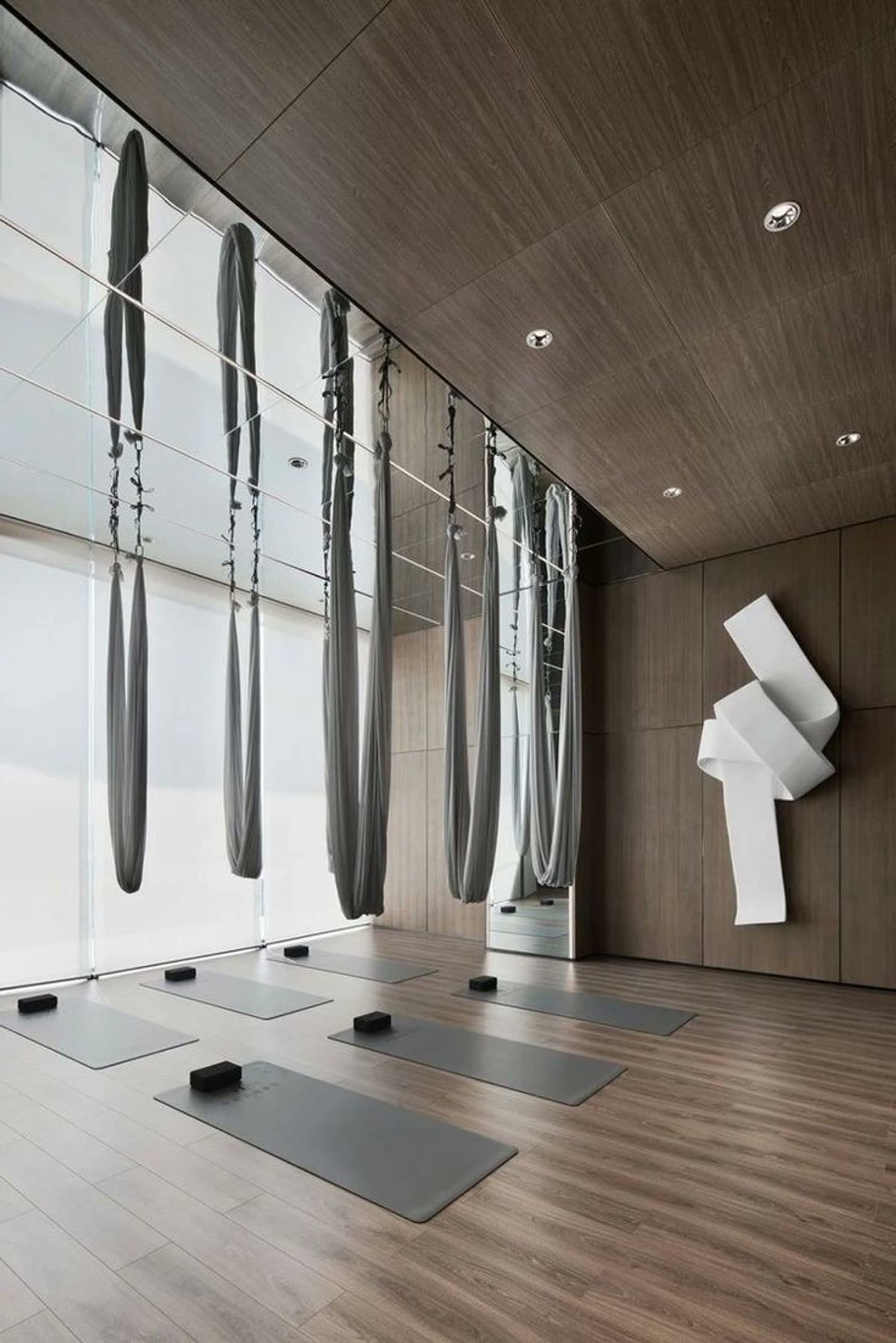 An empty movement studio with mats, blocks, and hanging silks